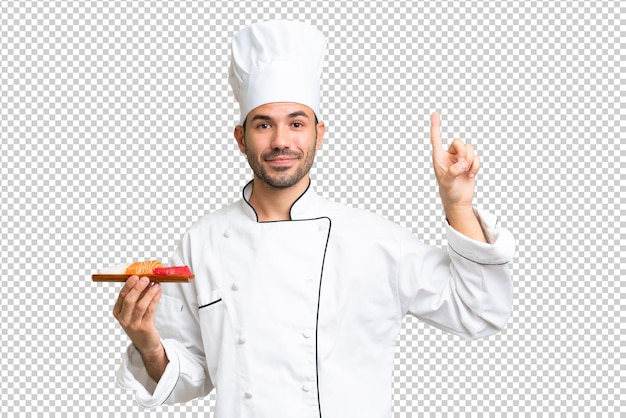 Joven chef caucásico sosteniendo un sushi sobre un fondo aislado que señala una gran idea