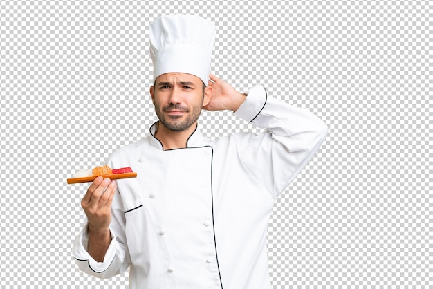 Joven chef caucásico sosteniendo un sushi sobre un fondo aislado que tiene dudas