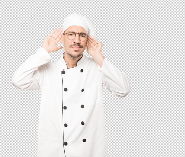 Joven chef concentrado haciendo un gesto de intentar escuchar algo