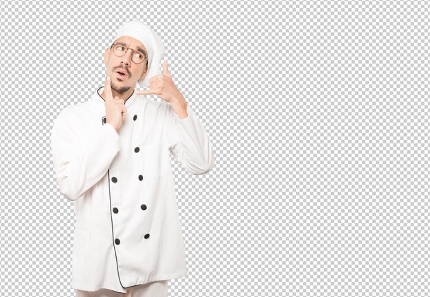Joven chef vacilante haciendo un gesto de llamar con la mano