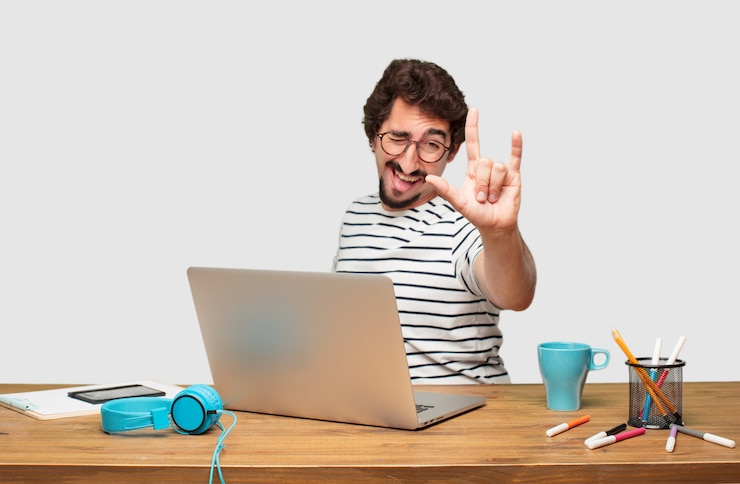PSD joven diseñador gráfico barbudo con una computadora portátil cantando rock, bailando, gritando