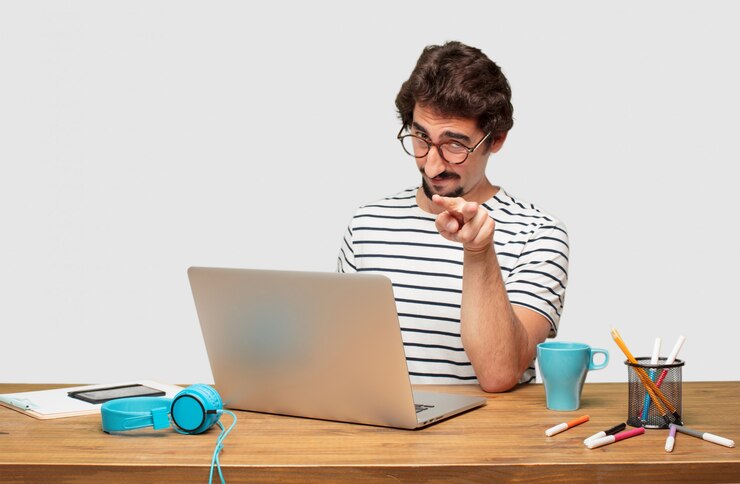 PSD joven diseñador gráfico barbudo con una computadora portátil mirando, observando, vigilando un objeto