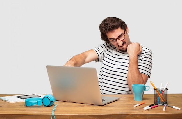 joven diseñador gráfico barbudo con una computadora portátil con una pose enojada, agresiva y amenazante