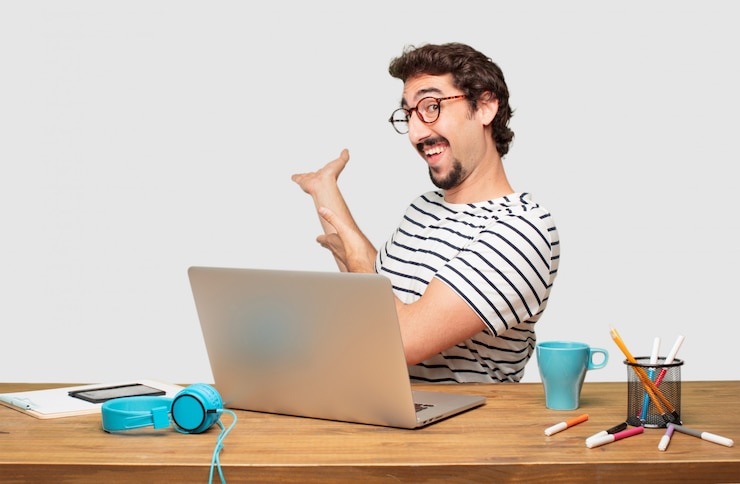PSD joven diseñador gráfico barbudo con una computadora portátil sonriendo con un aspecto orgulloso, satisfecho y feliz