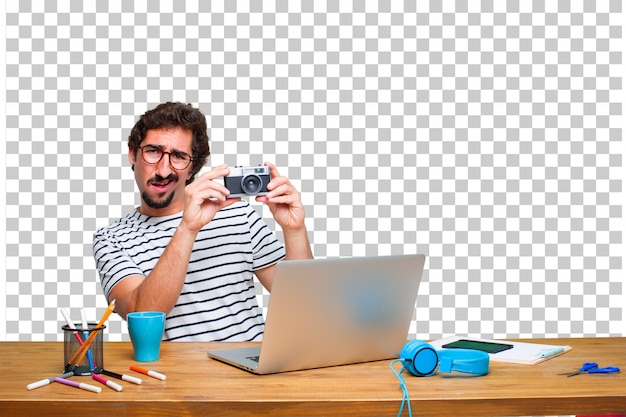 PSD joven diseñador gráfico loco en un escritorio con una computadora portátil y con una cámara vintage