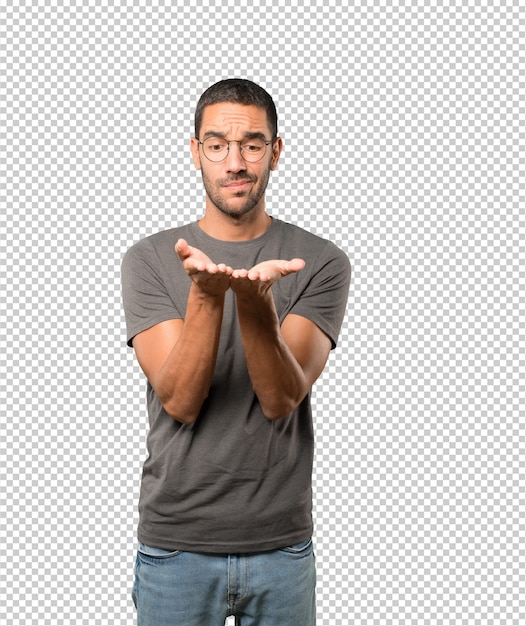 Joven dudoso sosteniendo algo con la mano