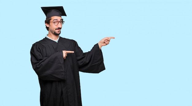 joven graduado riendo en voz alta con la cabeza inclinada hacia atrás y alegre, alegre expresión
