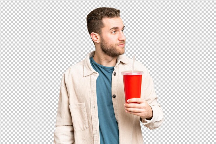 PSD joven hombre rubio guapo sosteniendo refresco sobre el fondo de la llave de croma aislada mirando hacia el lado