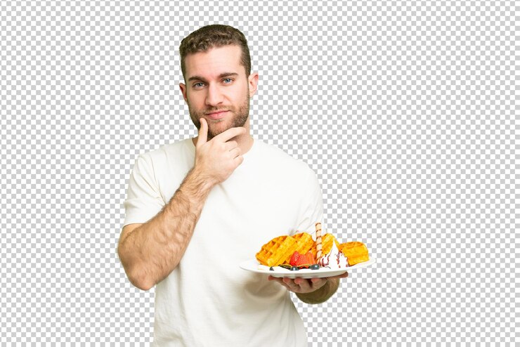 PSD joven hombre rubio guapo sosteniendo waffles sobre aislado pensamiento de fondo clave de croma