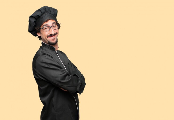 PSD joven loco como un chef de pie hacia los lados, con una mirada orgullosa, satisfecha y feliz en la cara, sonriendo