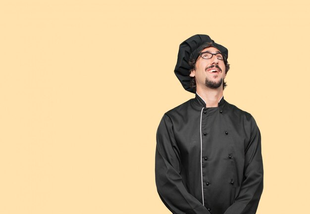 joven loco como un chef sonriendo y mirando hacia arriba, hacia el cielo