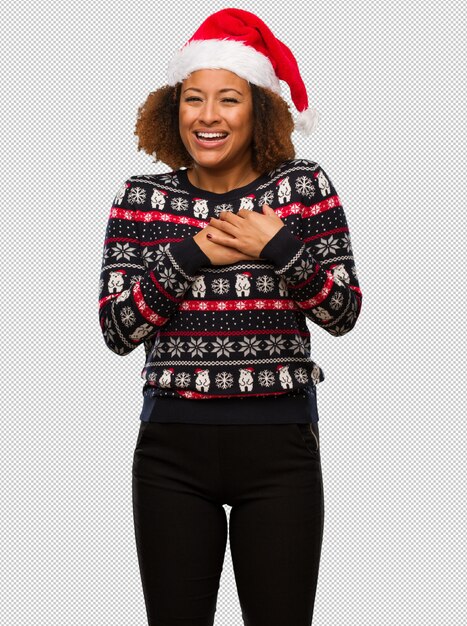 Joven mujer negra en un moderno suéter de navidad con estampado haciendo un gesto romántico