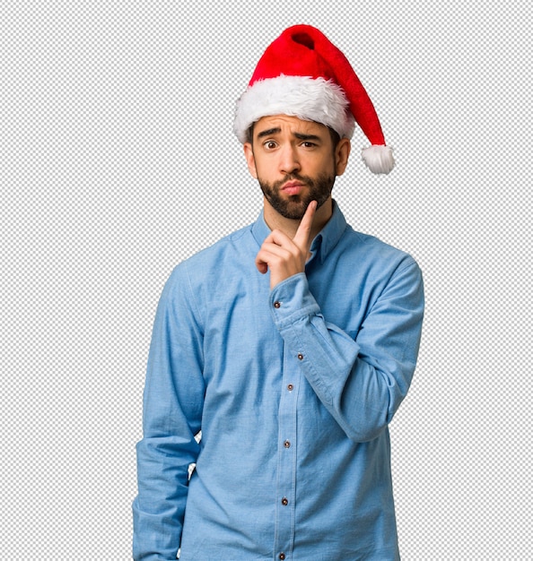 Joven con sombrero de santa dudando y confundido