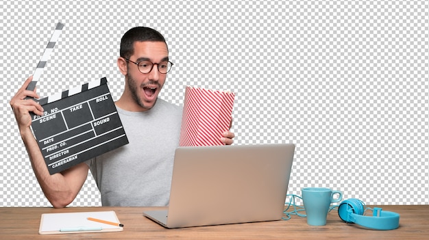 Joven sorprendido mirando una película en su computadora portátil y comiendo palomitas de maíz