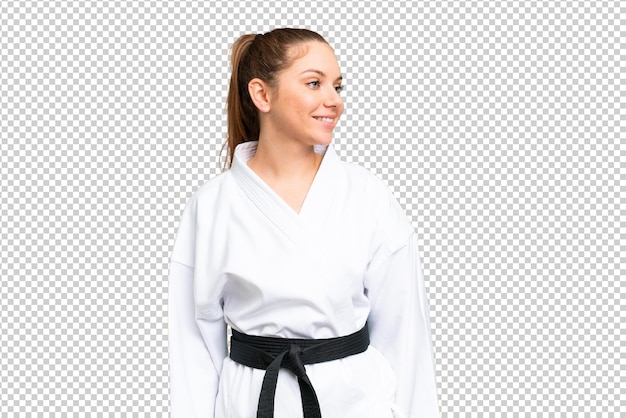 Junge blonde Frau, die Karate über isolierten Chromakey-Hintergrund macht, die nach der Seite schaut