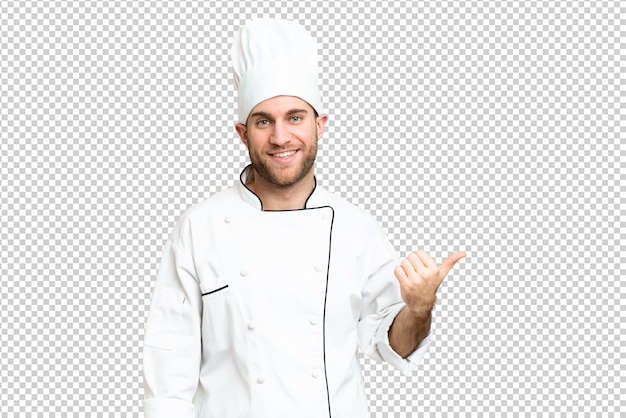Junge blonde Mann Koch über isolierter Chroma-Schlüssel-Hintergrund, der zur Seite zeigt, um ein Produkt zu präsentieren