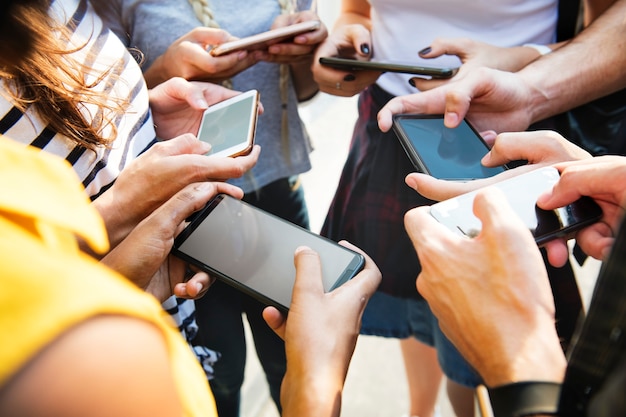 Junge erwachsene Freunde, die zusammen Jugendkulturkonzept der Smartphones draußen verwenden
