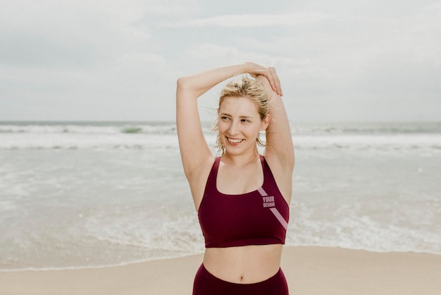Junge, glückliche Frau, die sich am Strand ausstreckt