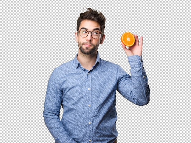 Junger Mann, der eine Orange anhält