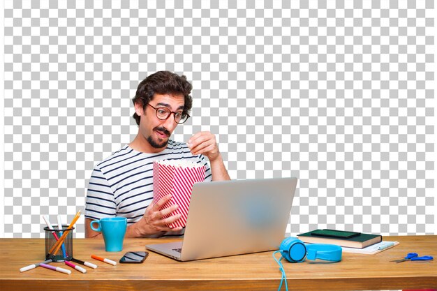 Junger verrückter Grafikdesigner auf einem Schreibtisch mit einem Laptop und mit einem Knallmaiseimer