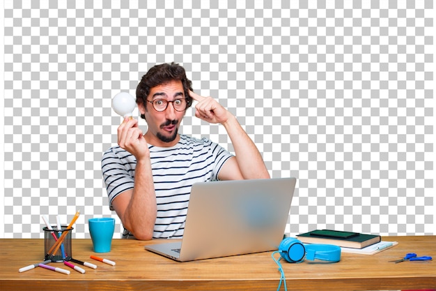 Junger verrückter Grafikdesigner auf einem Schreibtisch mit einem Laptop und mit einer Glühlampe. idee konzept