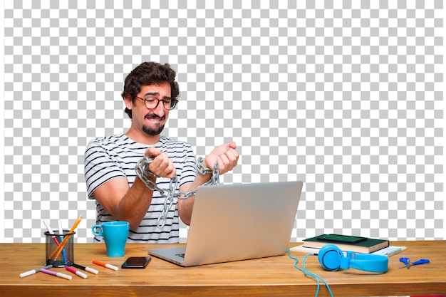 Junger verrückter Grafikdesigner auf einem Schreibtisch mit einem Laptop und mit einer Kette. Freiheitskonzept