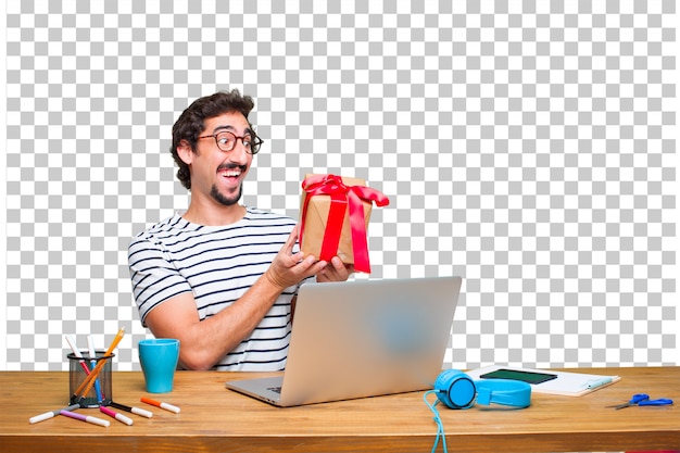 Junger verrückter grafikdesigner auf einem schreibtisch mit einem laptop und mit geschenkboxkonzept