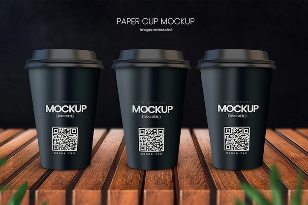 PSD kaffeetassenmodell aus papier mit drei tassen auf holztischplatte mit dunklem schwarz im hintergrund