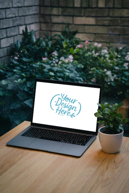 Laptop em mesa de madeira com planta e vista ao ar livre