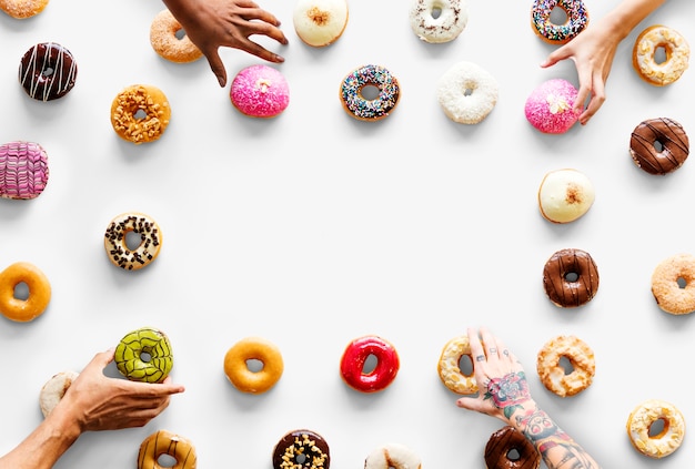 Le mani delle persone raggiungono le ciambelle