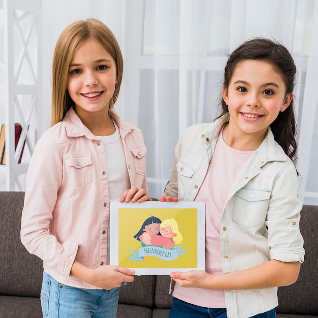Le migliori amiche che tengono insieme un tablet mock-up