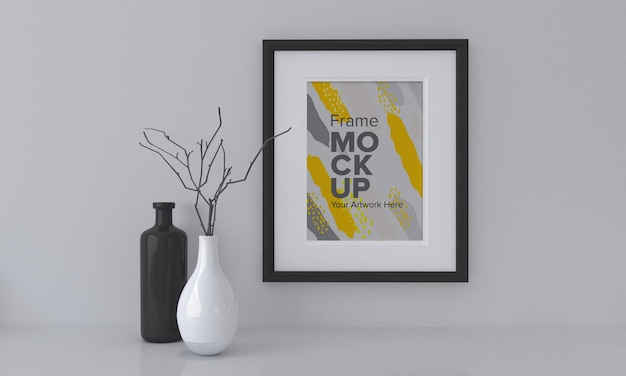 Libre d'une maquette de cadre noir à côté de vases sur un fond de mur gris