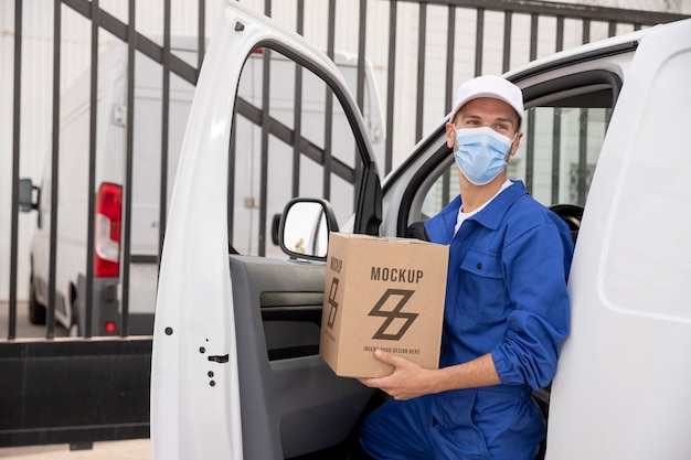 Lieferbote mit medizinischer Maskentragebox beim Aussteigen aus dem Lieferwagen