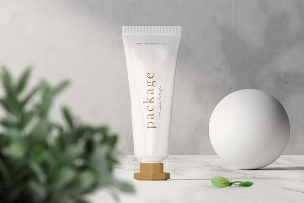 Limpe a maquete de embalagem de tubo de creme mínimo no topo com folhas e esfera.