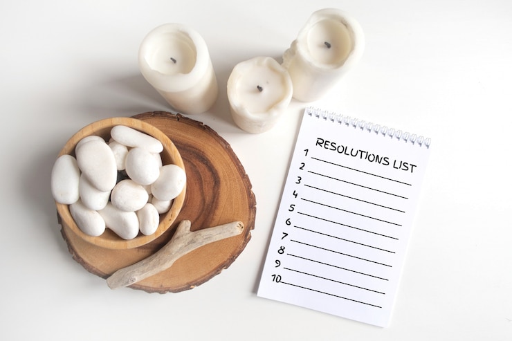 PSD lista de resoluciones vacías de año nuevo con un tazón de guijarros blancos y velas blancas en una tabla blanca.