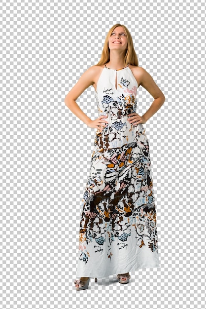 Loira jovem garota em um vestido de verão posando com os braços no quadril