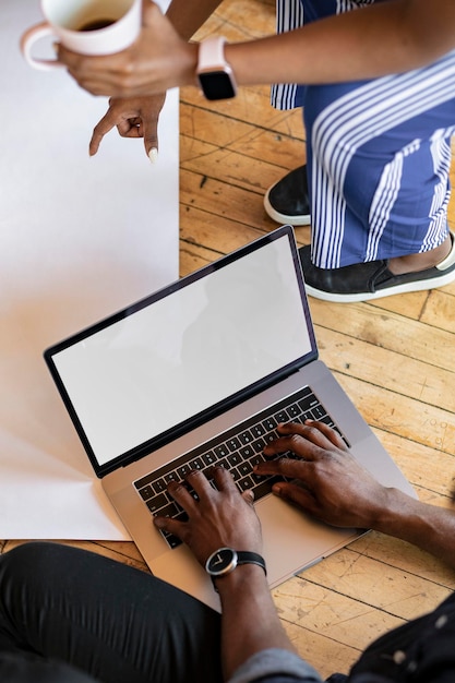 Mains tapant sur un clavier d'ordinateur portable sur une maquette de plancher en bois