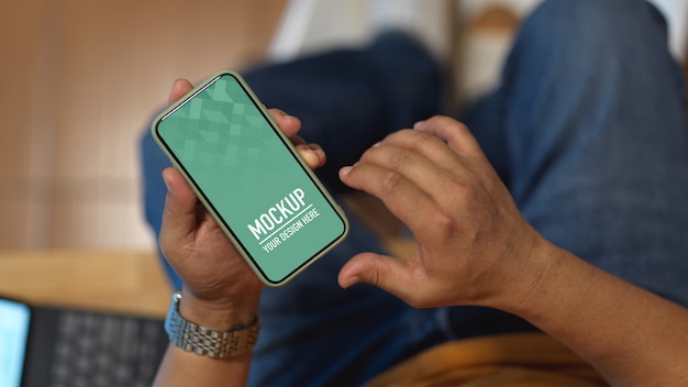 Mâle main à l'aide de smartphone maquette alors qu'il était assis dans la salle de bureau