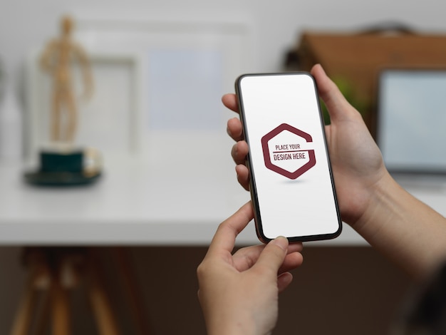 Mani dello studente utilizzando smartphone mockup in ufficio