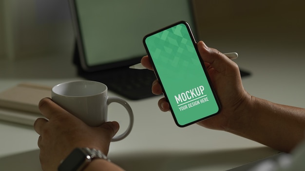 Mann, der Smartphone-Modell und Kaffeetasse hält