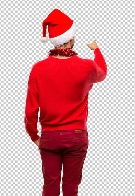 Mann mit roter Kleidung feiert die Weihnachtsfeiertage mit dem Zeigefinger zurück zeigend