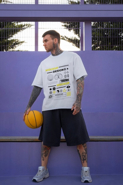 PSD mann trägt cyber-streetwear-t-shirt-attrappe mit urbanem design auf dem basketballplatz