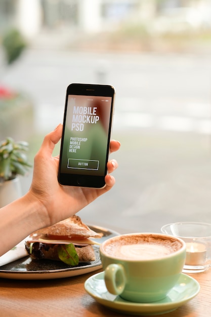 Mano che tiene il telefono cellulare a colazione