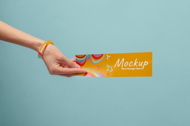 Mano con il braccialetto del festival di musica mock-up che tiene il biglietto del concerto