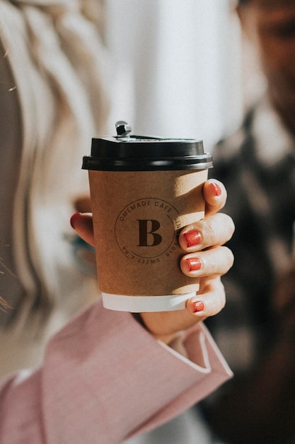 Mano femenina sosteniendo una maqueta de taza de café