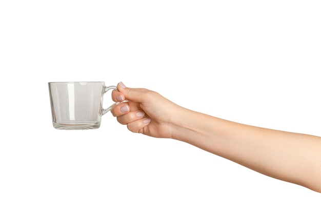 mano femenina sosteniendo una taza de vidrio vacía en un fondo vacío.