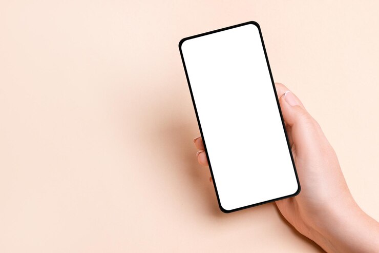 Mano femminile che tiene un telefono con uno schermo vuoto su uno sfondo beige