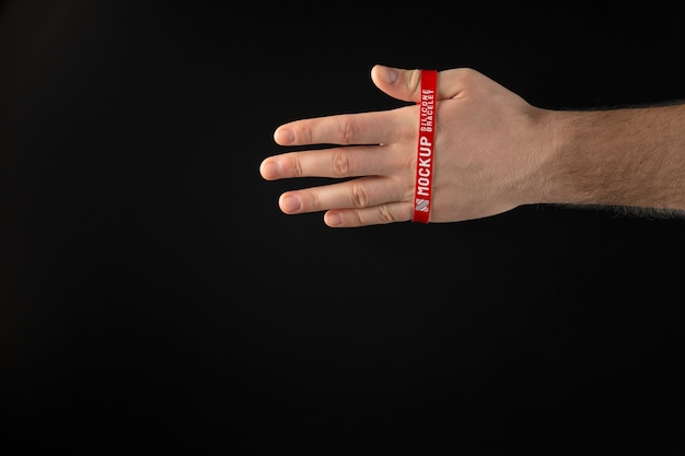 Mano con pulsera roja con fondo oscuro