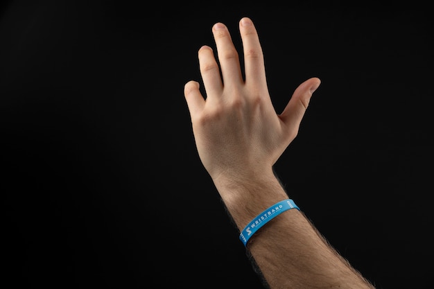 Mano realista con pulsera azul con fondo oscuro