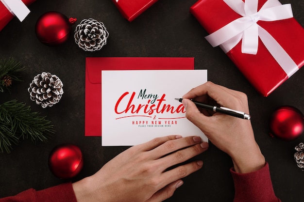 Manos escribiendo maqueta de tarjeta de felicitación de feliz Navidad